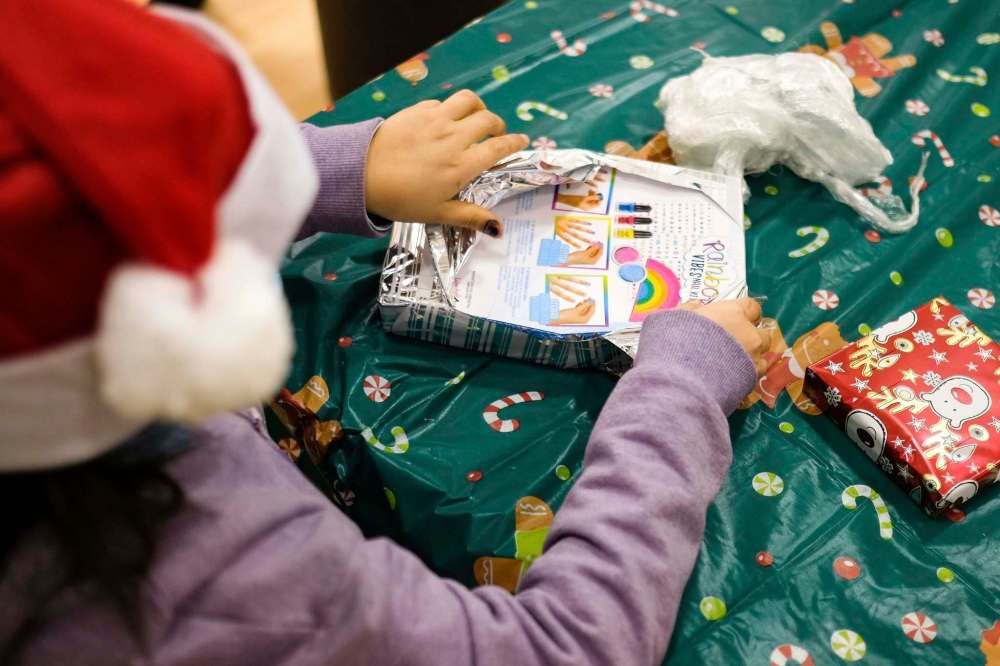 Daniel Crump / Winnipeg Free Press
A child finishes unwrapping a Christmas present as part of a game.