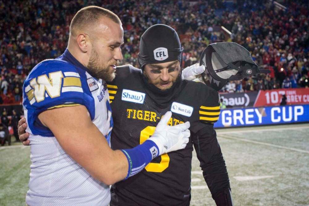 Winnipeg Blue Bombers Thiadric Hansen, left, comforts Hamilton Tiger-Cats quarterback Dane Evans after the CFL Grey Cup in 2019. Hansen has signed a one-year deal with the Bombers. THE CANADIAN PRESS FILES/Jeff McIntosh