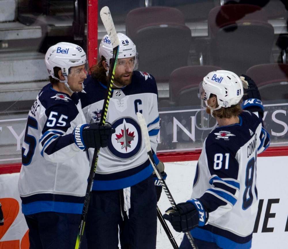 Winnipeg Jets' Mark Scheifele, left, and Kyle Connor, right, congratulate Blake Wheeler on his goal during second period NHL action against the Ottawa Senators on Thursday. THE CANADIAN PRESS/Adrian Wyld