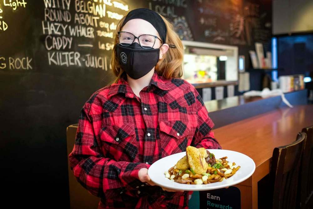 Daniel Crump / Winnipeg Free Press
Hilary Colins, kitchen manager at Le Garage, holds a plate of French onion poutine, the eatery’s twist on the French-Canadian classic.
