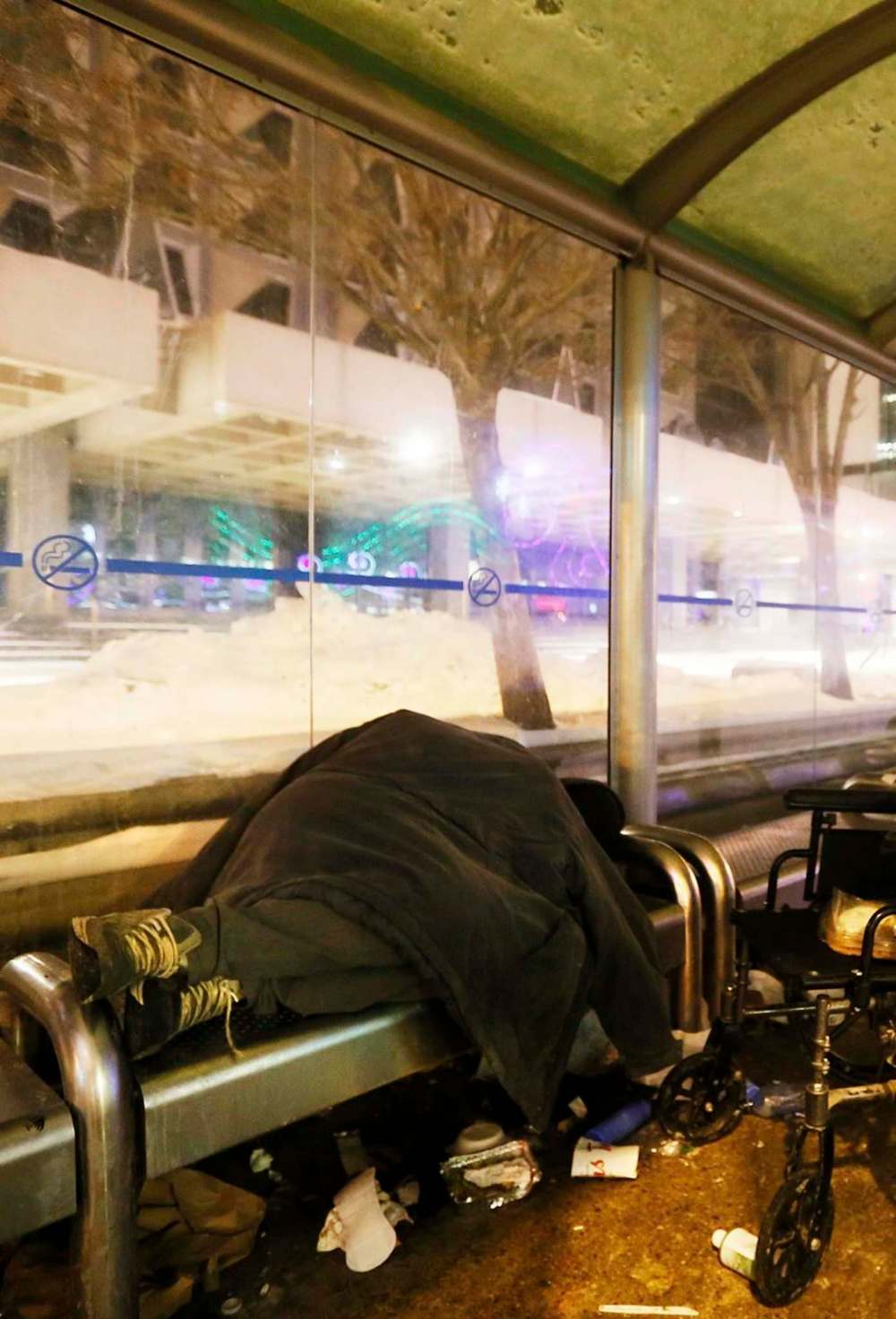 A person rests in a downtown Winnipeg bus shelter. (John Woods / Winnipeg Free Press files)