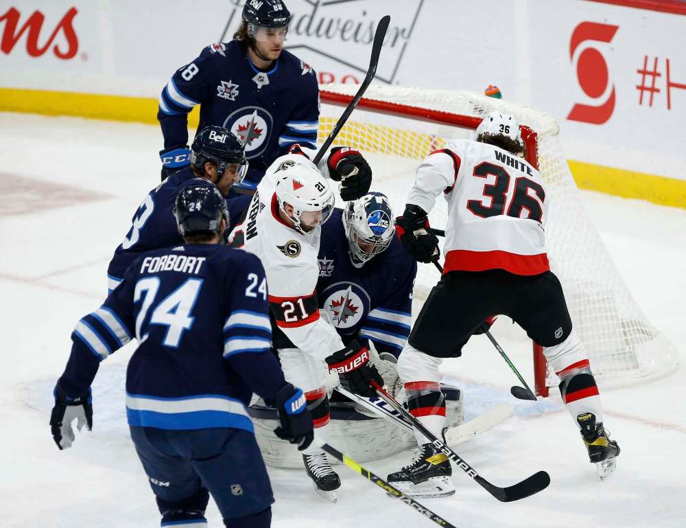John Woods / The Canadian Press
Winnipeg Jets goaltender Connor Hellebuyck (37) saves the shot as Ottawa Senators’ Derek Stepan (21) and Colin White (36) attack during first period NHL action in Winnipeg on Thursday.