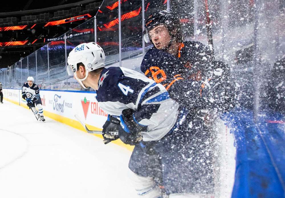 Jason Franson / The Canadian Press
Edmonton's Kailer Yamamoto is checked by Neal Pionk during the second period Monday.