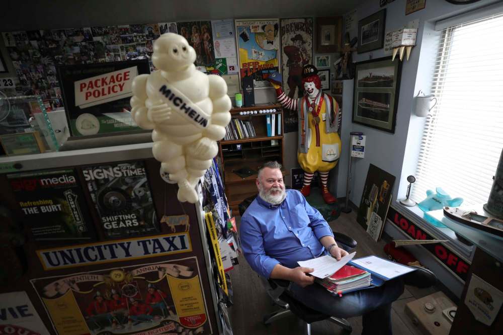RUTH BONNEVILLE / WINNIPEG FREE PRESS
Shane Storie, owner SRS Signs, sits in his shop surrounded by a huge array of local antiquated signs, billboards, mascots and plaques he has collected over the years.
