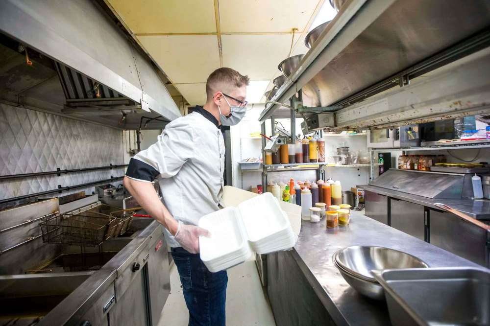 MIKAELA MACKENZIE / WINNIPEG FREE PRESS
Little Bones Wings chef Gerald Baker with takeout containers, which have also increased in price.
