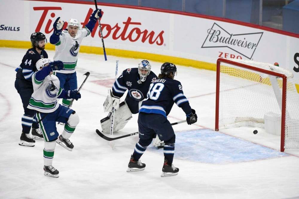 Vancouver Canucks' Nils Hoglander celebrates his goal in front of Winnipeg Jets goaltender Connor Hellebuyck during the first period. THE CANADIAN PRESS/Fred Greenslade