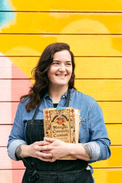 Jo Snyder, author of The Vegan Mennonite Kitchen, holds her grandma Lena&rsquo;s well-used copy of the Mennonite Community Cookbook by Mary Emma Showalter, which inspired the creation of her first cookbook. (Supplied)