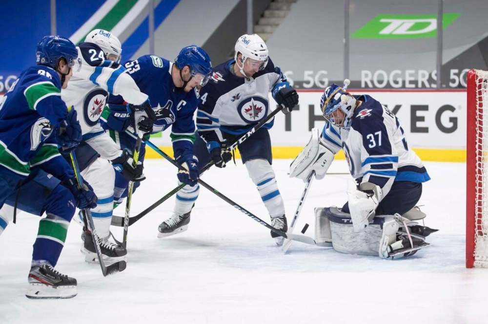 Winnipeg Jets goalie Connor Hellebuyck makes one of his 38 saves on Vancouver Canucks' Bo Horvat shot as Neal Pionk and Derek Forbort defend during the second period in Vancouver, on Wednesday. THE CANADIAN PRESS/Darryl Dyck