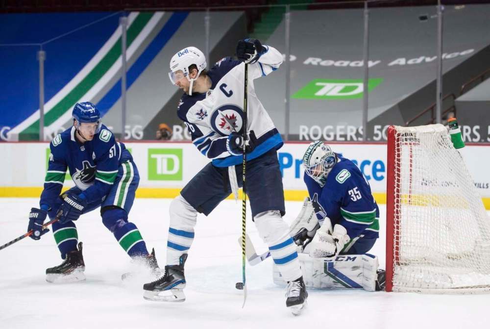 Winnipeg Jets' Blake Wheeler tips the puck while Vancouver's Tyler Myers and Thatcher Demko watch during the first period. THE CANADIAN PRESS/Darryl Dyck
