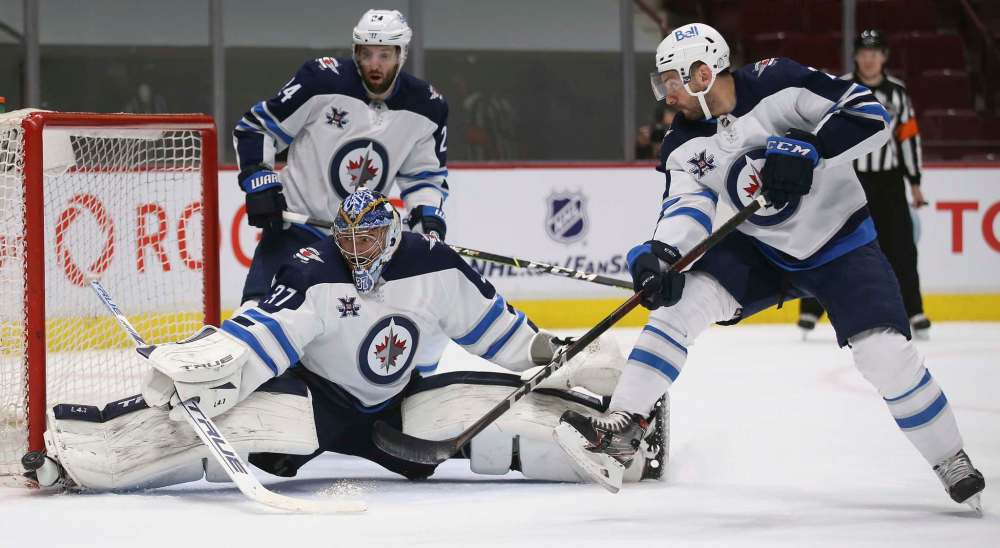 Winnipeg Jets' goaltender Connor Hellebuyck stretches out to make a save during the second period against the Vancouver Canucks' in Vancouver, Wednesday. (TREVOR HAGAN / WINNIPEG FREE PRESS)