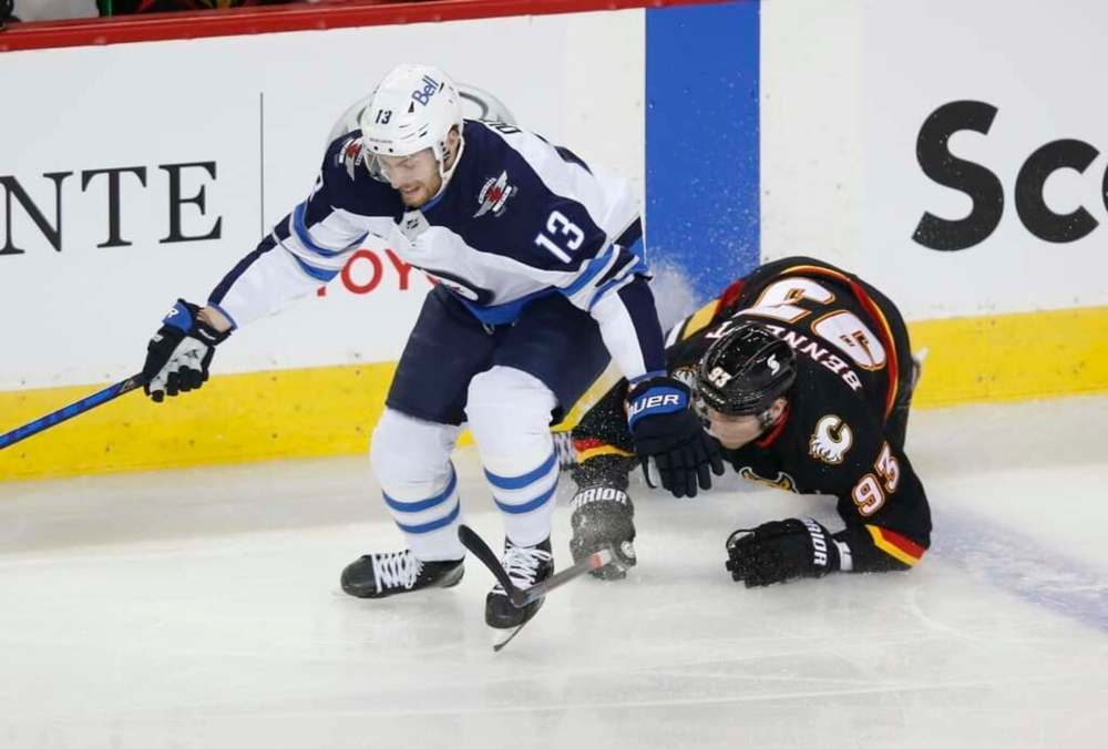 Winnipeg Jets' Pierre-Luc Dubois, left, and Calgary Flames' Sam Bennett battle for the puck during the first period in Calgary, Friday. THE CANADIAN PRESS/Todd Korol