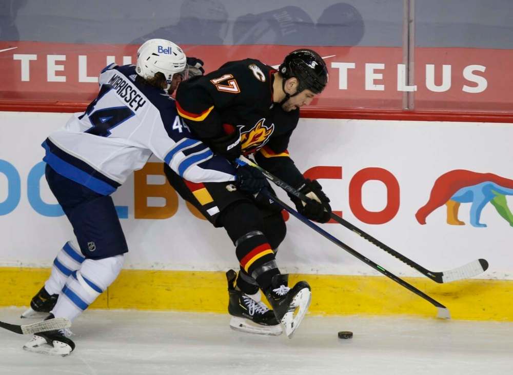 Winnipeg Jets' Josh Morrissey and Calgary Flames' Milan Lucic battle for the puck during the third period. THE CANADIAN PRESS/Todd Korol