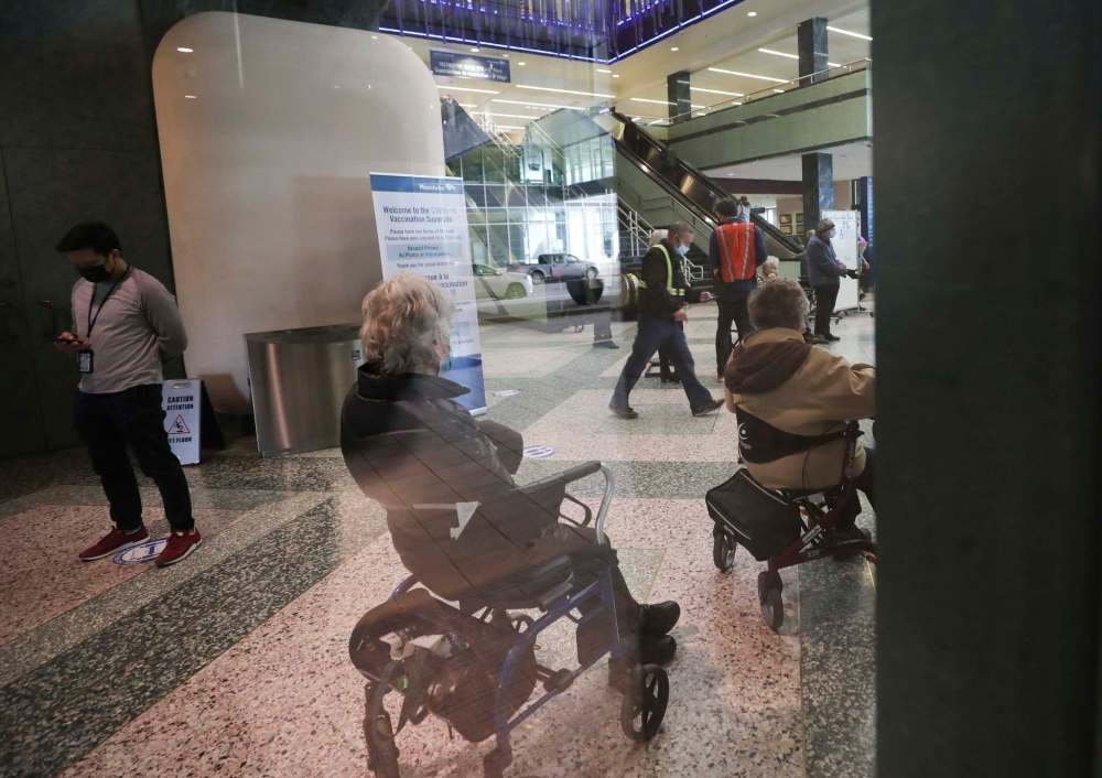 RUTH BONNEVILLE / WINNIPEG FREE PRESS People wait their turn in line as seen through the window of the main floor of the vaccination centre at The RBC Convention Centre Thursday.