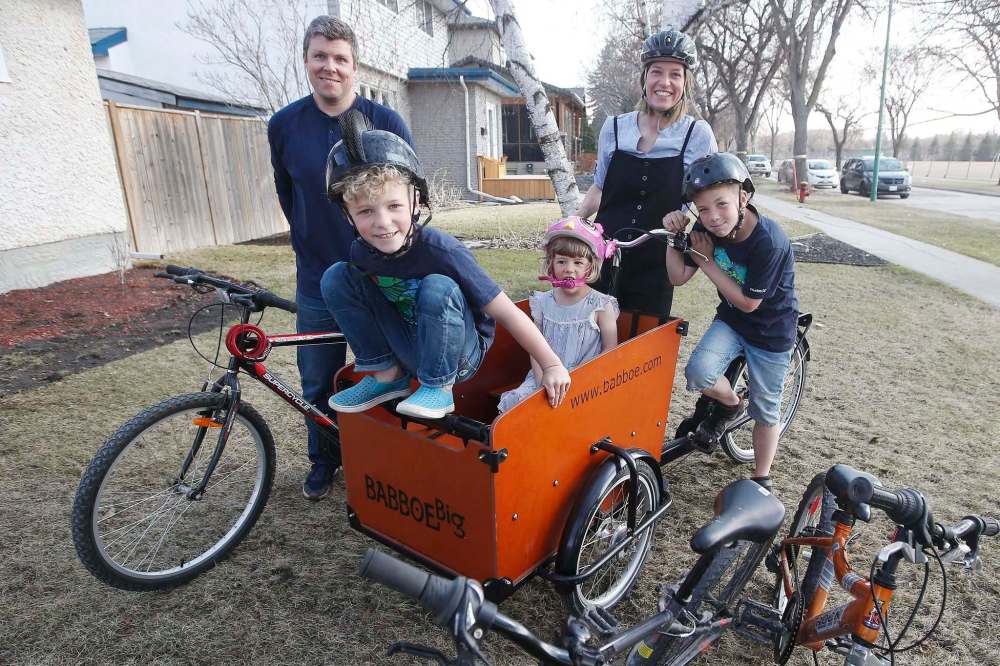 Meghan and Justin Cameron with their children (from left), Magnus, Beatrix and Griffin and their cargo bike. The family invested in the bike to transport their kids and to pick up groceries. (John Woods / Winnipeg Free Press)