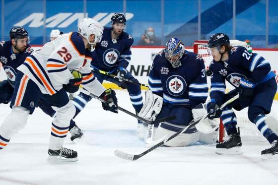 Winnipeg Jets goaltender Connor Hellebuyck saves a shot by Edmonton Oilers' Leon Draisaitl as Jets' Mason Appleton defends during the first period in Winnipeg on Wednesday. THE CANADIAN PRESS/John Woods