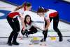 Team Canada skip Kerri Einarson makes a shot in a game against Estonia as lead Briane Meilleur (left) and second Shannon Birchard sweep. (Jeff McIntosh / The Canadian Press)