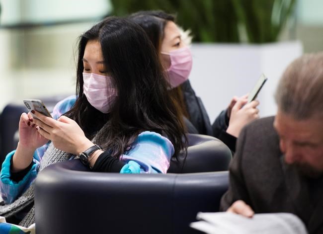 People wear masks as a precaution due to the coronavirus outbreak as they wait for the arrivals at the International terminal at Toronto Pearson International Airport in Toronto on Saturday, January 25, 2020.THE CANADIAN PRESS/Nathan Denette