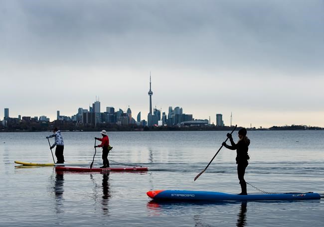 People physical distance while stand-up paddleboarding in Humber Bay on Lake Ontario during the COVID-19 pandemic in Toronto on Sunday, May 10, 2020. THE CANADIAN PRESS/Nathan Denette
