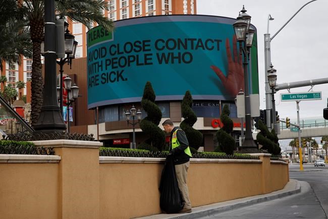 A worker cleans up in front of the Palazzo hotel as a sign warns to avoid contact with sick people after casinos have been ordered to shut down along the Las Vegas Strip due to the coronavirus Wednesday, March 18, 2020, in Las Vegas. For most people, the new coronavirus causes only mild or moderate symptoms, such as fever and cough. For some, especially older adults and people with existing health problems, it can cause more severe illness, including pneumonia. (AP Photo/John Locher)