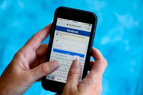 FILE - In this Aug. 21, 2018, file photo, a Facebook start page is shown on a smartphone in Surfside, Fla. Facebook says it's working to help limit the spread of misinformation and harmful content about the coronavirus and will focus on providing helpful information to people. Kang-Xing Jin, Facebook's head of health, said in a post, Friday, Jan. 31, 2020, that the social media platform's third-party fact-checkers are reviewing content and debunking false claims related to the coronavirus. (AP Photo/Wilfredo Lee, File)