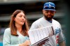 FILE - Los Angeles Dodgers announcer Alanna Rizzo, left, delivers a report before the first inning of a baseball game against the Colorado Rockies in Denver, with Dodgers left fielder Matt Kemp looking on in Denver, in this Sunday, June 3, 2018, file photo. Rizzo is returning to MLB Network, and will be a regular contributor on Christopher Russo's “High Heat” show. (AP Photo/David Zalubowski, File)
