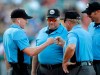 FILE - In this July 10, 2019, file photo, home plate umpire Brian deBrauwere, left, huddles with officials while wearing an earpiece connected to a ball and strikes calling system before the Atlantic League All-Star minor league baseball game in York, Pa. DeBrauwere wore the earpiece connected to an iPhone in his ball bag which relayed ball and strike calls upon receiving it from a TrackMan computer system that uses Doppler radar. The independent Atlantic League became the first American professional baseball league to let the computer call balls and strikes during the all star game. Umpires agreed to cooperate with Major League Baseball in the development and testing of an automated ball-strike system as part of a five-year labor contract announced Saturday, Dec. 21, two people familiar with the deal told The Associated Press. The Major League Baseball Umpires Association also agreed to cooperate and assist if Commissioner Rob Manfred decides to utilize the system at the major league level. The people spoke on condition of anonymity because those details of the deal, which is subject to ratification by both sides, had not been announced. (AP Photo/Julio Cortez)