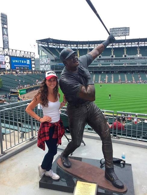 In this photo provided by Vince Adamo, Chicago White Sox fan Gabby Adamo poses beside a statue of Frank Thomas at Guaranteed Rate Field in Chicago. Adamo rooted for the White Sox throughout a three-year battle with leukemia. But she never got to attend an opening day game featuring her favorite team. Eight months after she died at the age of 22, her parents and the White Sox are doing what they can to rectify that. With no spectators permitted at stadiums due to the coronavirus pandemic, the White Sox are among the Major League Baseball teams giving fans the opportunity to fill some seats with their photographs on cutouts. So when the White Sox open July 24 against the Minnesota Twins, in the stands will be a cutout featuring a smiling Gabby Adamo wearing a White Sox jersey and cap. (Vince Adamo via AP)