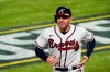 FILE - Atlanta Braves' Freddie Freeman smiles after scoring on a hit by Marcell Ozuna against the Los Angeles Dodgers during the sixth inning in Game 4 of a baseball National League Championship Series in Arlington, Texas, in this Thursday, Oct. 15, 2020, file photo. Freeman won't report with the Atlanta Braves position players on Tuesday, Feb. 23, 2021, following the births of his twin boys. Manager Brian Snitker said Monday he supports Freeman arriving later in the week.(AP Photo/Tony Gutierrez, File)