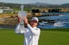 FILE - In this Feb. 9, 2020, file photo, Nick Taylor, of Canada, holds up his trophy on the 18th green of the Pebble Beach Golf Links after winning the AT&T Pebble Beach National Pro-Am golf tournament in Pebble Beach, Calif. The win got him into his first Masters, but Taylor will miss out on the roars without spectators. (AP Photo/Eric Risberg, File)