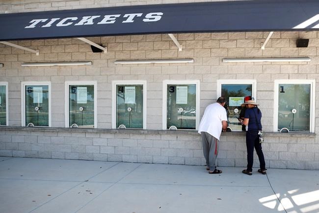 Baseball fans stand at the window for ticket refunds outside Hammond Stadium, Monday, March 16, 2020, in Fort Myers, Fla., after Major League Baseball suspended the rest of its spring training game schedule because of the coronavirus outbreak. Big league managers say that Major League Baseball has instructed them to prepare for spring training to start on time in mid-February despite uncertainty around the coronavirus. Tampa Bay Rays manager Kevin Cash said Wednesday, Dec. 16, 2020, that officials from the commissioner's office had a meeting with managers Tuesday an expressed optimism about opening spring camps as scheduled. (AP Photo/Elise Amendola)