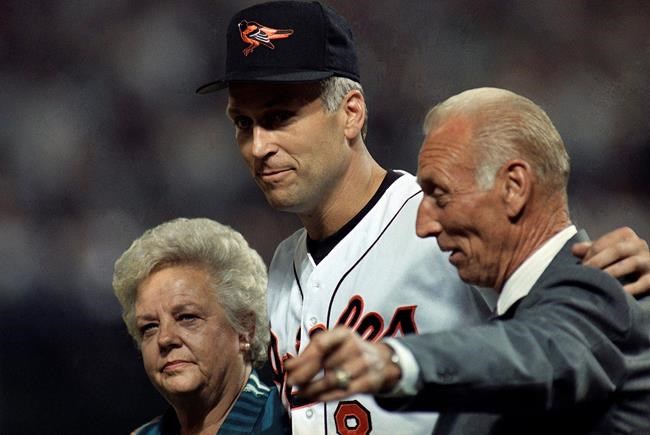 FILE - In this Sept. 6, 1995, file photo, Baltimore Orioles shortstop Cal Ripken, Jr., center, walk onto the field with his parents Violet, left, and Cal Ripken Sr. for postgame ceremonies in Baltimore. Cal Jr. broke Lou Gehrig's record of 2,130 consecutive games Sept. 6 as the Orioles defeated the California Angeles. Vi, matriarch of the famed Orioles family that includes Hall of Fame son Cal Jr. and once the victim of a bizarre kidnapping, has died. She was 82. Family spokesman John Maroon said she died Friday, Feb. 26, 2021, a day before her birthday. (AP Photo/Denis Paquin, File)