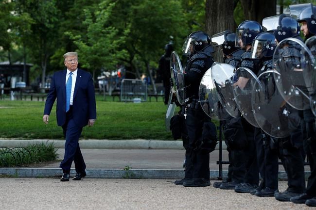 FILE - In this Monday, June 1, 2020, file photo, President Donald Trump walks past police in Lafayette Park after visiting outside St. John's Church across from the White House in Washington. Part of the church was set on fire during protests on Sunday night. (AP Photo/Patrick Semansky, File)