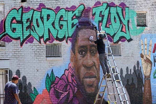 In this Sunday, June 7, 2020, photo, Zack Murray paints a mural honoring George Floyd, on the side of a building in Houston’s Third Ward. Floyd, who grew up in the Third Ward, died after being restrained by Minneapolis police officers on Memorial Day. (AP Photo/David J. Phillip)