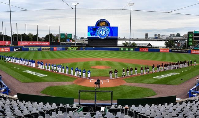 Toronto Blue Jays and Baltimore Orioles players line up on their baselines before a baseball game in Buffalo, N.Y., Friday, Aug. 28, 2020. All players and coaches wore No. 42 uniforms in honor of Jackie Robinson Day around the league. (AP Photo/Adrian Kraus)