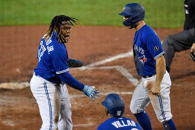 Toronto Blue Jays' Vladimir Guerrero Jr., left, and Randal Grichuk, right, celebrate after scoring against the New York Yankees on a double by Alejandro Kirk during the sixth inning of a baseball game in Buffalo, N.Y., Thursday, Sept. 24, 2020. (AP Photo/Adrian Kraus)