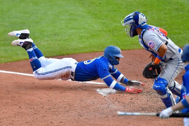Toronto Blue Jays' Jonathan Villar, left, scores a run as New York Mets catcher Robinson Chirinos waits for the throw during the sixth inning of a baseball game in Buffalo, N.Y., Sunday, Sept. 13, 2020. (AP Photo/Adrian Kraus)