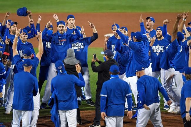 Toronto Blue Jays players, coaches and staff celebrate a 4-1 win over the New York Yankees in a baseball game in Buffalo, N.Y., Thursday, Sept. 24, 2020. Toronto clinched a postseason berth with the win. (AP Photo/Adrian Kraus)