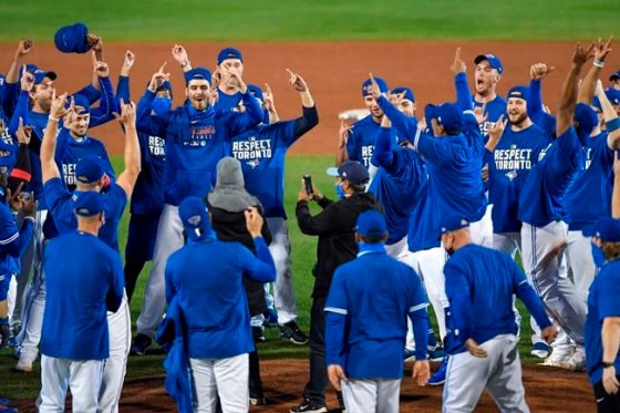 Toronto Blue Jays players, coaches and staff celebrate a 4-1 win over the New York Yankees in a baseball game in Buffalo, N.Y., Thursday, Sept. 24, 2020. Toronto clinched a postseason berth with the win. (AP Photo/Adrian Kraus)