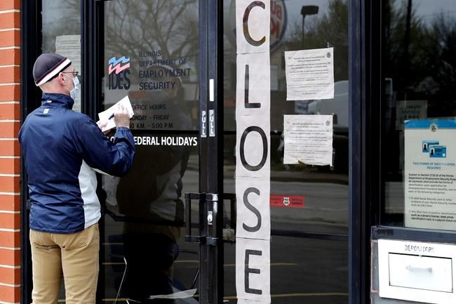 FILE - In this April 30, 2020 file photo, a man writes information in front of Illinois Department of Employment Security in Chicago. U.S. businesses cut an unprecedented 20.2 million jobs in April, an epic collapse with coronavirus outbreak closing the offices, factories, schools, construction sites and stores that propel the U.S. economy. The Wednesday, May 6, report from payroll company ADP showed the tragic depth and scale of job losses that left no part of the world’s largest economy unscathed. (AP Photo/Nam Y. Huh, File)