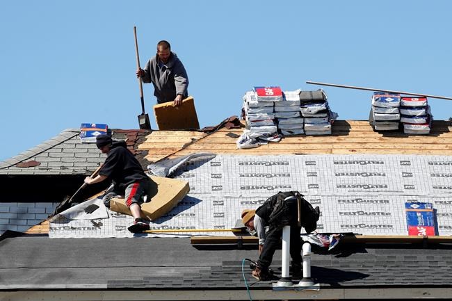 FILE - In this April 2, 2020 file photo, roofers work on removing and placing new shingles in Warren, Mich. U.S. home-building activity collapsed in March as the coronavirus spread, with housing starts tumbling 22.3% from a month ago. The Commerce Department said Thursday, April 16, that ground breakings occurred last month at a seasonally adjusted annual rate of 1.2 million units, down from a 1.56 million pace in February. (AP Photo/Paul Sancya, File)