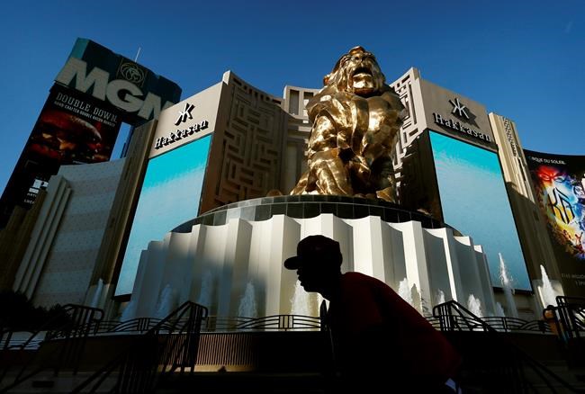 FILE - In this Aug. 3, 2015, file photo, a man rides his bike past the MGM Grand hotel and casino in Las Vegas. MGM Resorts plans to lay off 18,000 workers as the casino company struggles with the fallout from the pandemic. The Las Vegas-based parent of the Bellagio said in a letter to employees that furloughed employees will keep health benefits until Sept. 30, 2020 according to a report in The Wall Street Journal. (AP Photo/John Locher, File)
