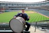 FILE - In this April 27, 2011, file photo, Cleveland Indians fan John Adams poses in his usual centerfield bleacher seat with his ever-present bass drum before a baseball game between the Indians and the Kansas City Royals in Cleveland. Adams, who will miss his first home opener since 1955 on Friday due to the coronavirus, has been keeping the beat for the Indians since 1973. AP Photo/Amy Sancetta, File)