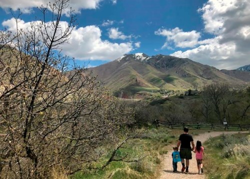 This April 22, 2020 image released by Lindsay Whitehurst, shows her husband Dave Watson walking with their two children, ages 3, left, and 5, on a trail in suburban Salt Lake City. When the coronavirus pandemic hit, Watson suddenly became a full-time dad. Outside “adventures” became the centerpieces of their days, giving him a front-row seat to the workings of their growing minds. (Lindsay Whitehurst via AP)