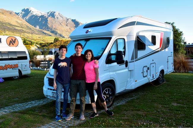 This Dec. 23, 2019, photo shows the Foster family, from left, Miles, 16, Jacob, 17, and Mio, posing in front of their rented camper van at Mrs. Woolly’s Campground in Glenorchy, New Zealand. Touring in a camper van is a popular way for tourists to see the country. (Malcolm Foster via AP)