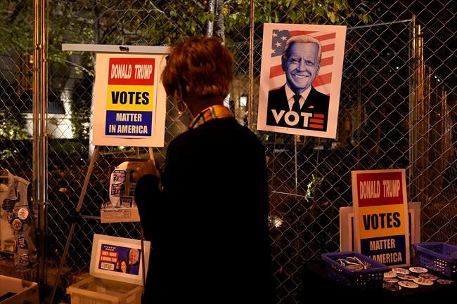 A vendor looks over her inventory while selling election signs and pins at Black Lives Matter Plaza, Friday, Nov. 6, 2020, in Washington. (AP Photo/Jacquelyn Martin)