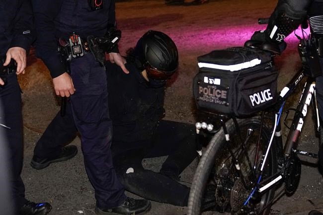 A demonstrator sits on the pavement after having been arrested by NYPD officers during a march through the West Village, Thursday, Nov. 5, 2020, in New York. (AP Photo/Seth Wenig)