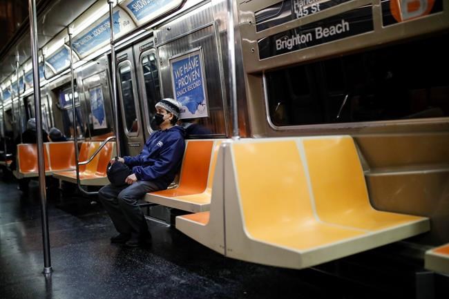 A commuter wears a face mask while riding the a nearly empty subway car into Brooklyn, Thursday, March 12, 2020, in New York. New York City Mayor Bill de Blasio said Thursday he will announce new restrictions on gatherings to halt the spread of the new coronavirus in the coming days, but he hopes to avoid closing all public events such as Broadway shows. For most people, the new coronavirus causes only mild or moderate symptoms. For some it can cause more severe illness. (AP Photo/John Minchillo)