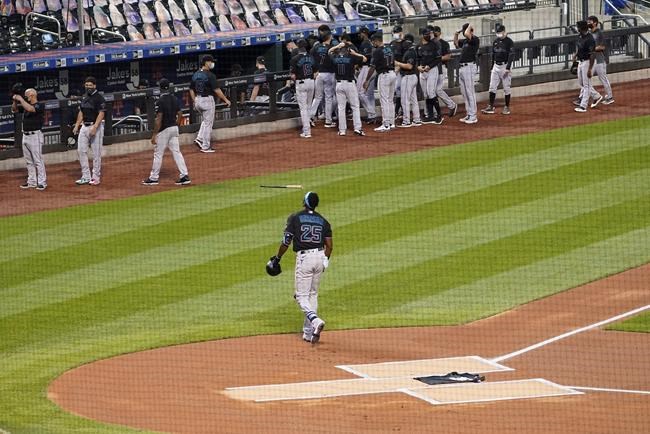 Miami Marlins center fielder Lewis Brinson walks away from home plate after placing a Black Lives Matter T-shirt on home plate as his teammates and the New York Mets walk off the field Thursday, Aug. 27, 2020, in New York. The Mets and Marlins jointly walked off the field after a moment of silence as they chose not to start their scheduled baseball game Thursday night. (AP Photo/John Minchillo)