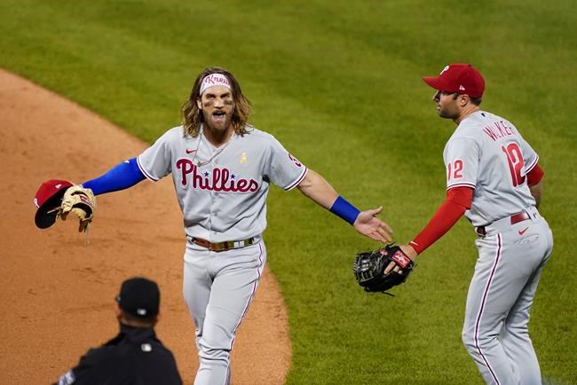 Philadelphia Phillies' Bryce Harper, left, questions umpire Roberto Ortiz, as Phillies' Neil Walker, right, watches during the fifth inning of a baseball game against the New York Mets, Saturday, Sept. 5, 2020, in New York. Harper was ejected. (AP Photo/John Minchillo)