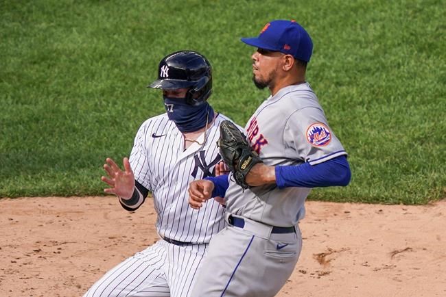 New York Yankees' Clint Frazier, left, scores the game-winning run on a wild pitch by New York Mets relief pitcher Dellin Betances, right, to close the ninth inning of a baseball game, Saturday, Aug. 29, 2020, in New York. The Yankees won 2-1. (AP Photo/John Minchillo)